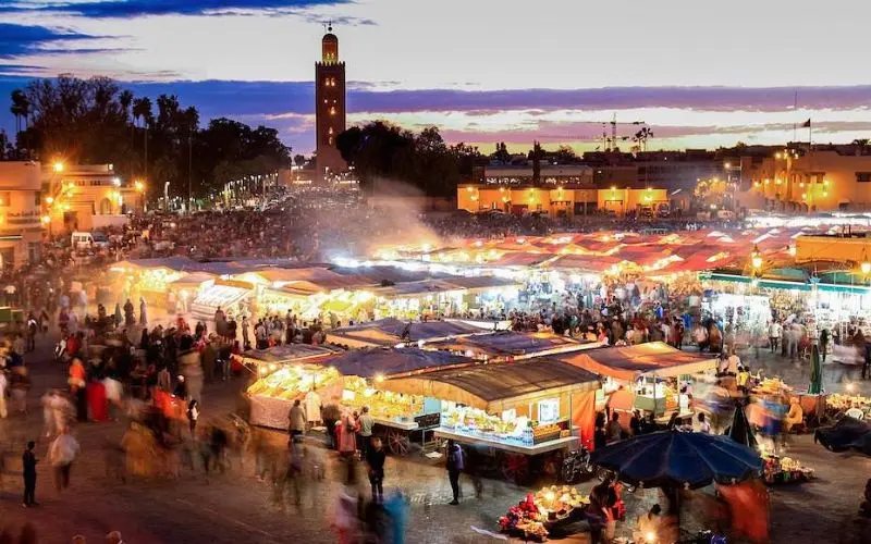 Busy evening scene at Jemaa el-Fnaa square in Marrakech with food stalls and crowds.