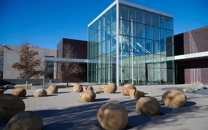 Modern glass building with stone sphere sculptures at the North Dakota Heritage Center & State Museum.