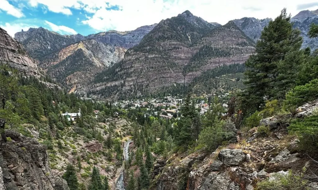 A view of Box Canyon Waterfall & Park surrounded by rocky cliffs and forest.