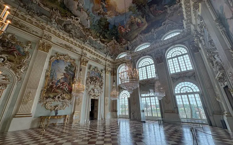 Ornate hall with chandeliers and painted ceiling inside Nymphenburg Palace.