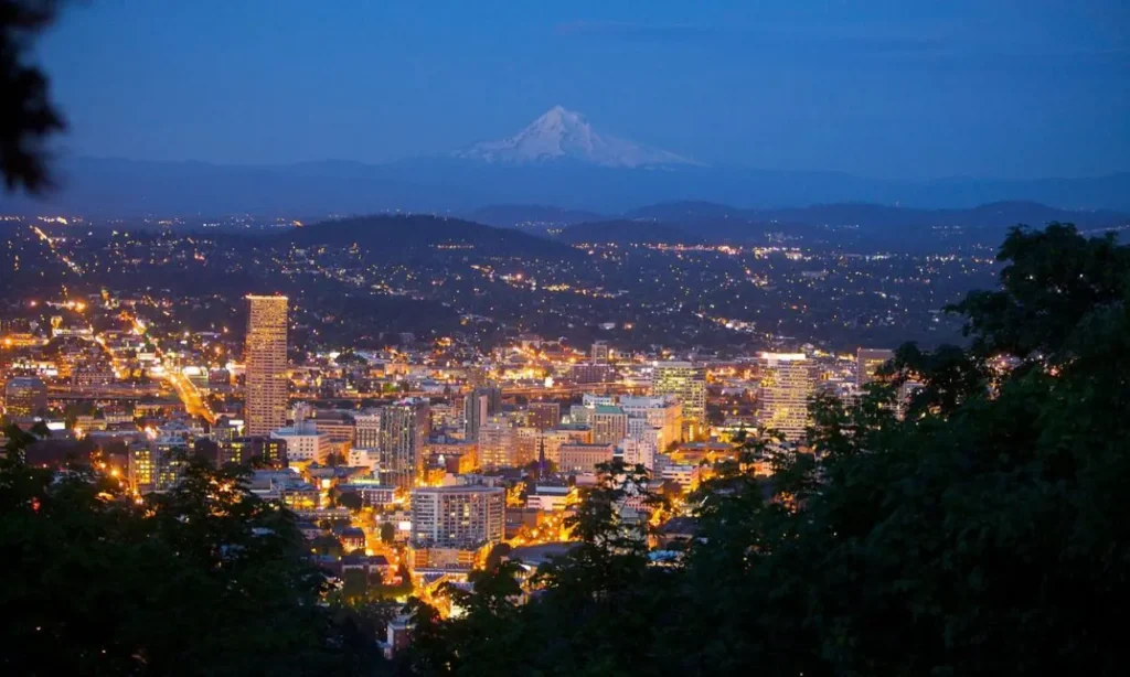 City lights glowing at dusk with Mount Hood in the background in Portland.
