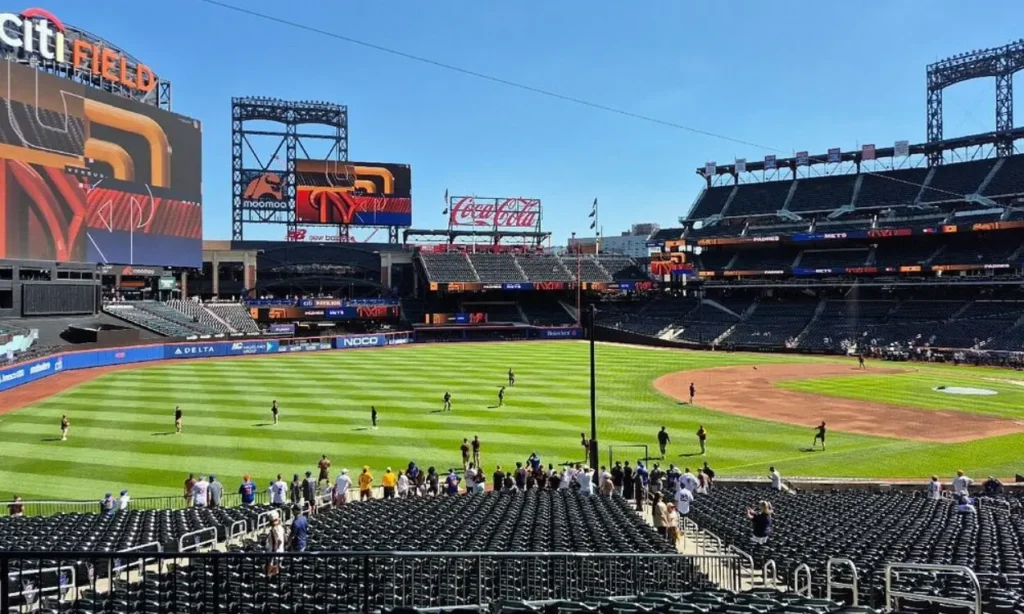 Baseball fans watch players warming up on the field at Citi Field.