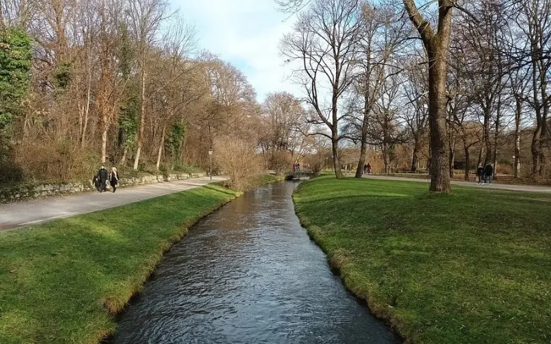 Stream running through the Englischer Garten with paths and bare trees.