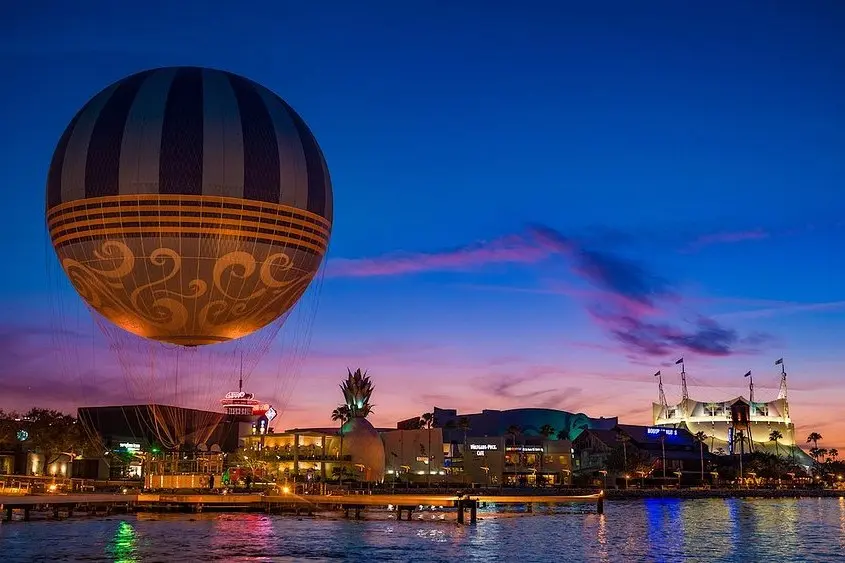 A giant tethered hot air balloon above Disney Springs at sunset.