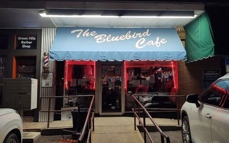A blue awning marks the entrance of The Bluebird Cafe at night.