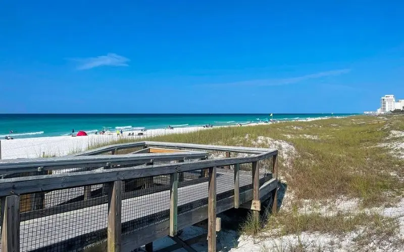 Wooden boardwalk leading to the white sand and blue water at Henderson Beach State Park.