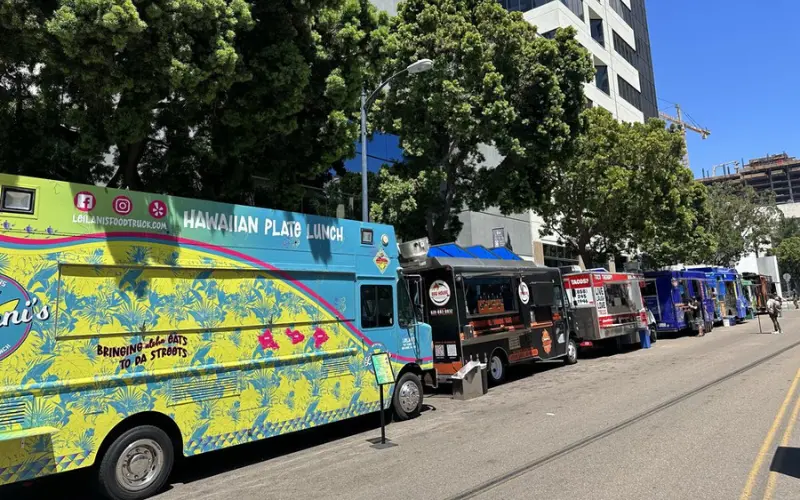 A row of colorful food trucks lines the street in San Diego.