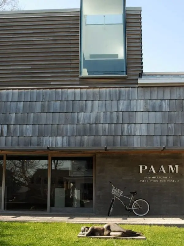 Exterior of Provincetown Art Association and Museum with a bike and sculpture on the lawn.