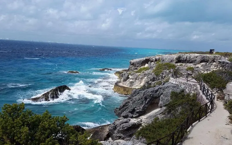 Waves crash against rocky cliffs along the coast of Isla Mujeres.