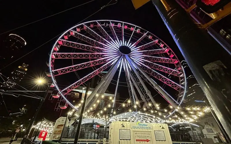 SkyView Atlanta Ferris wheel lit up at night with string lights below.