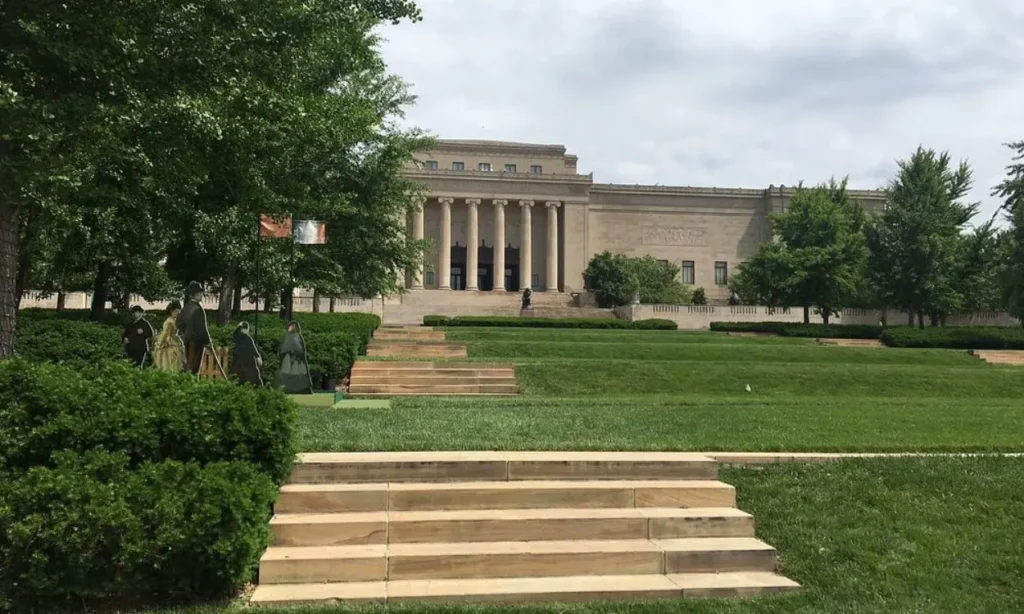 The columned building of The Nelson-Atkins Museum of Art with trees and steps in front.