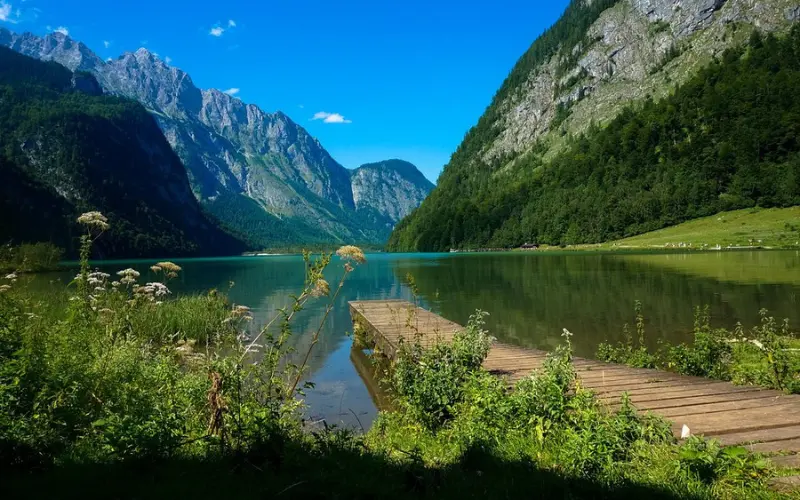 Wooden dock on the clear green waters of Königssee surrounded by mountains.