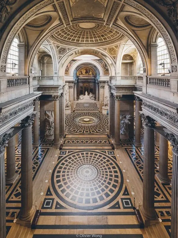 Interior of the Panthéon in Paris with domed ceiling, columns, and patterned marble floor.