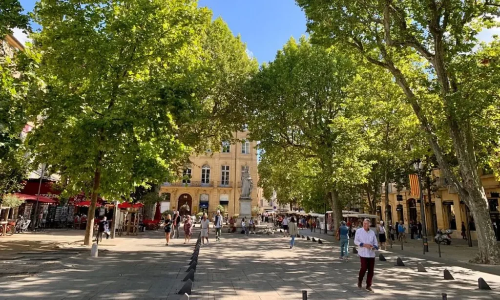People stroll along the tree-lined Cours Mirabeau surrounded by shops and cafés.