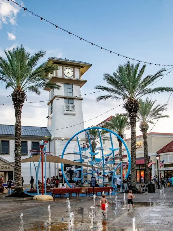 Families enjoying the shops, clock tower, and splash fountains at Destin Commons.