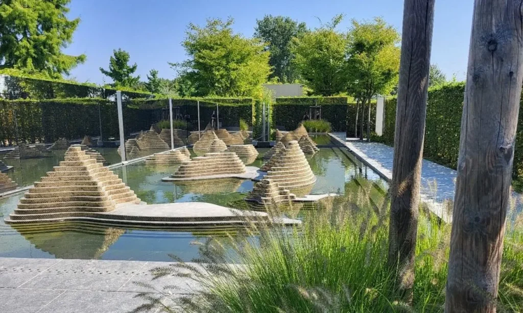Tiered stone structures in a reflective pond surrounded by greenery at Erholungspark Marzahn.