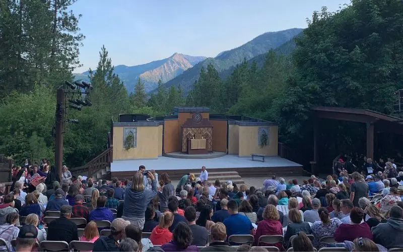 Outdoor theater with a crowd gathered in front of a mountain backdrop at Leavenworth Summer Theater.