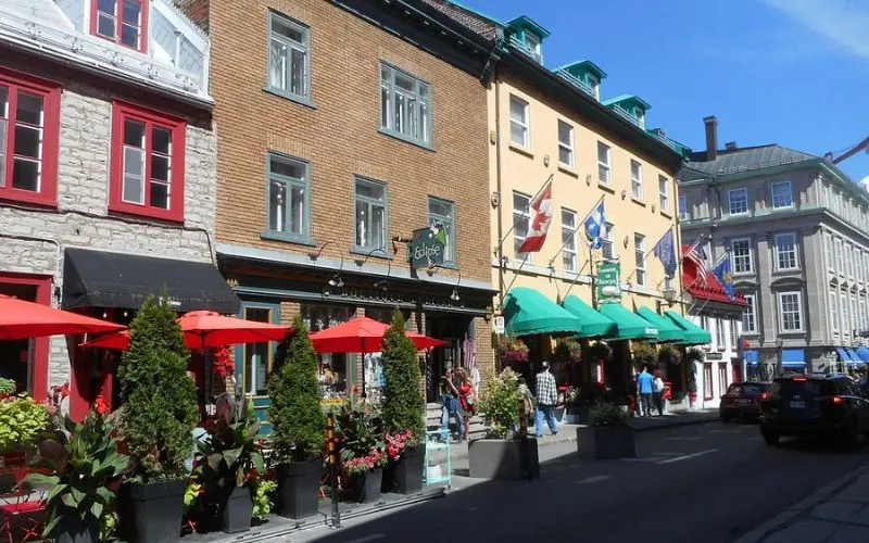 Colorful historic street lined with shops and flags in Quebec City.