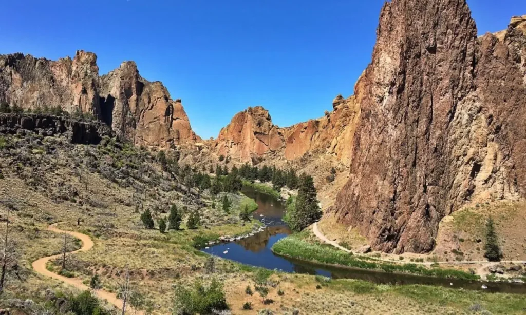 Towering rock formations and winding river under a clear blue sky at Smith Rock State Park.