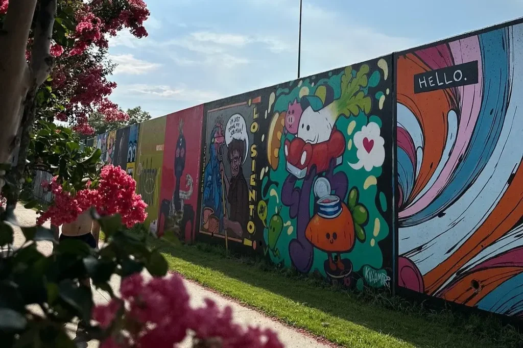 Colorful street art murals line a wall along the Atlanta BeltLine walking path.