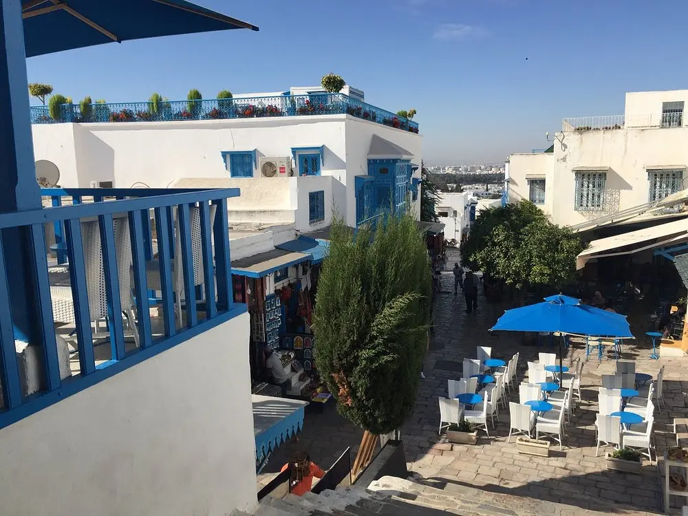 A sunny view of Café des Nattes in Sidi Bou Said with blue and white chairs and umbrellas.