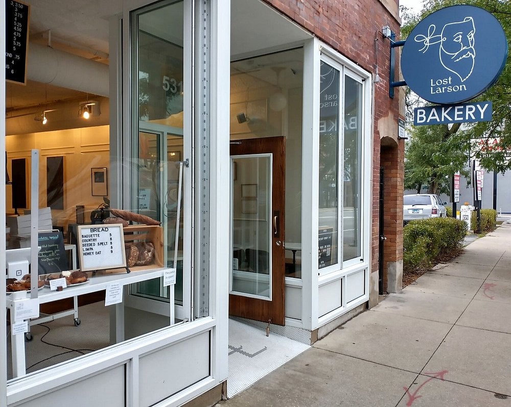 Lost Larson bakery storefront with a blue sign and fresh bread displayed in the window.