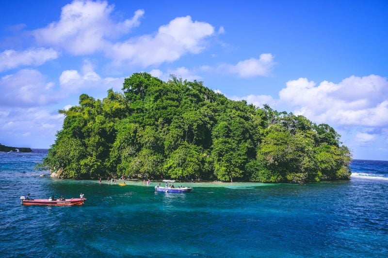 Serene beach scene in Port Antonio, with palm trees and turquoise ocean, one of the most beautiful places in Jamaica