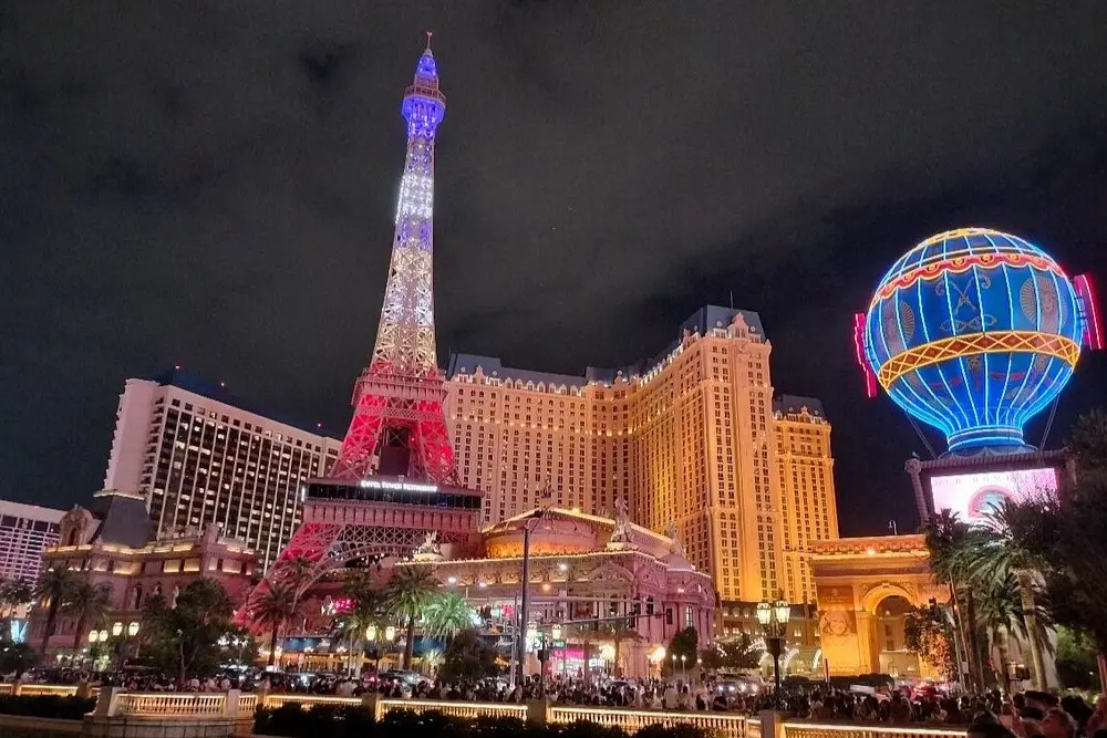 The Paris Las Vegas Hotel on the Las Vegas Strip lit up at night with its replica Eiffel Tower and neon balloon.