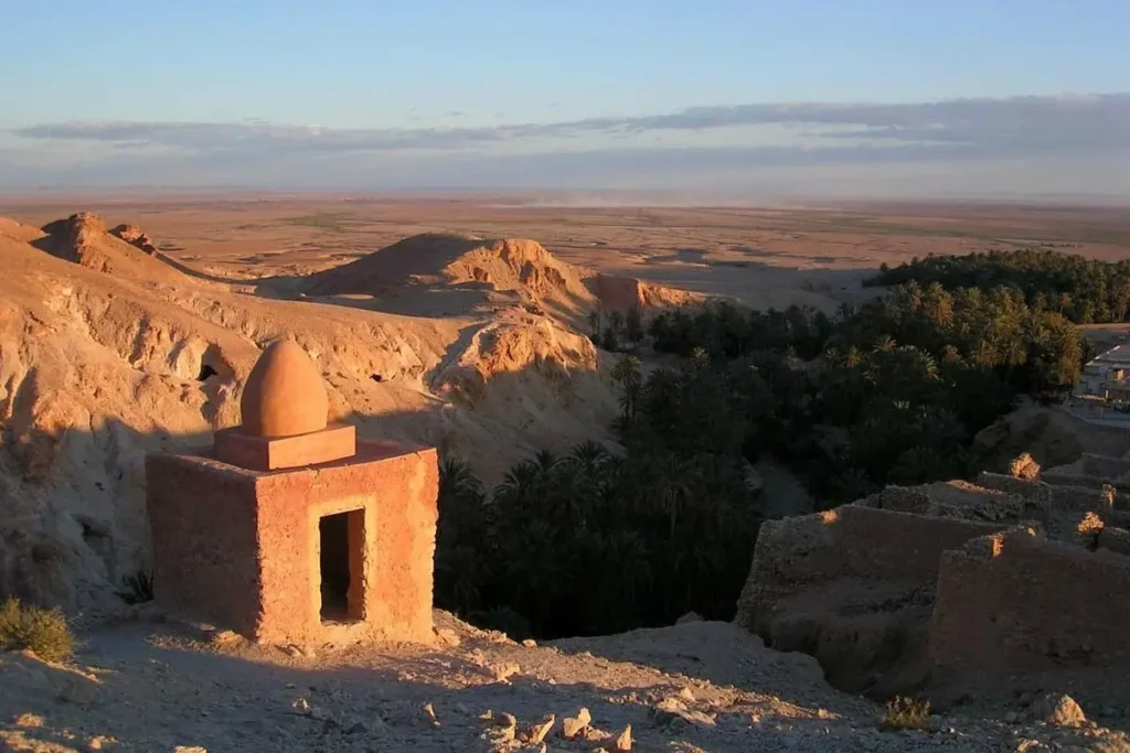 A scenic view of Tozeur with desert hills, palm groves, and traditional architecture.