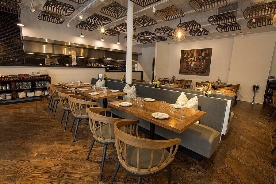 Elegant dining room at Virtue with wooden tables, cozy seating, and an open kitchen.