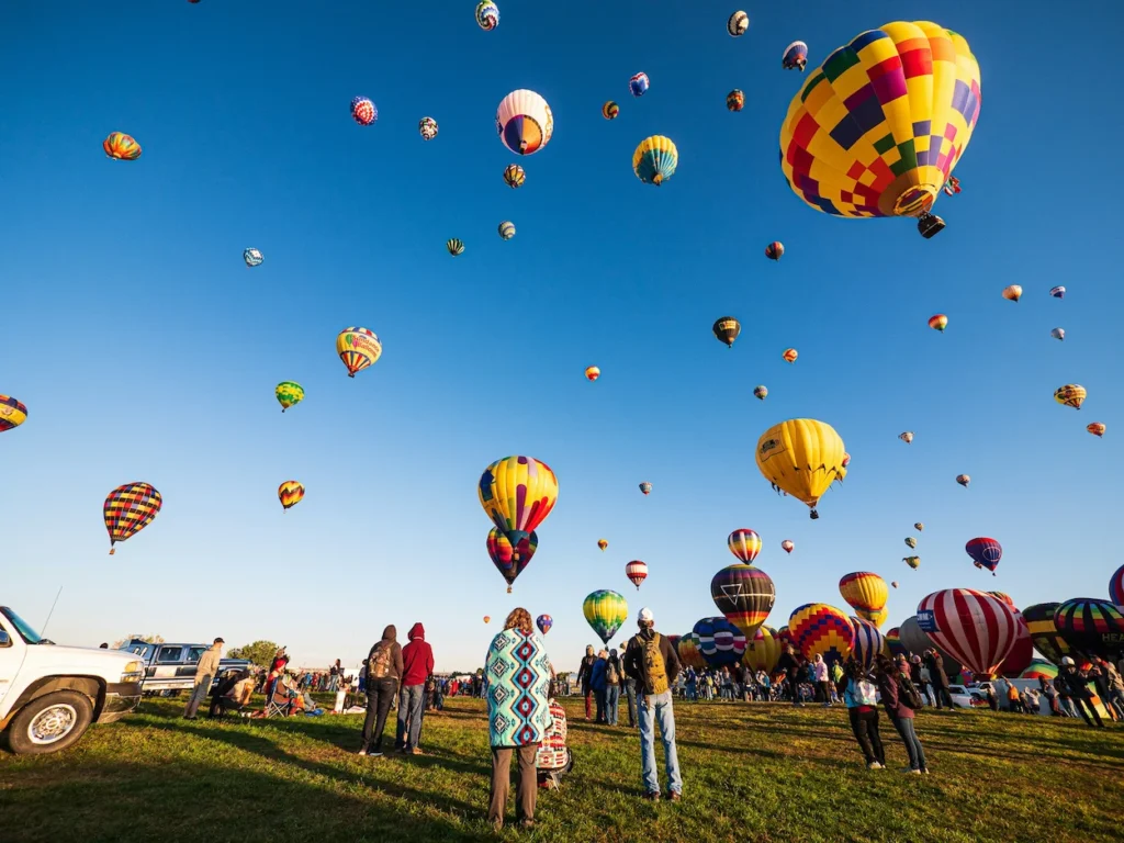 Dozens of colorful hot air balloons floating together over the Albuquerque launch field