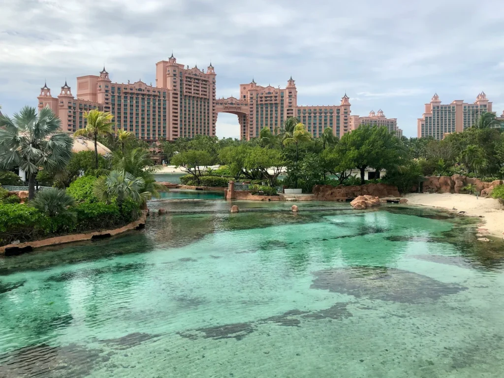Pink towers of Atlantis resort rising behind a clear turquoise lagoon and tropical palm trees in the Bahamas