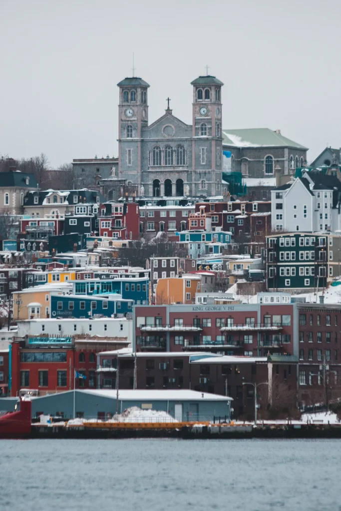 Basilica of St. John the Baptist rising above colorful, snow-dusted hillside houses in St. John's