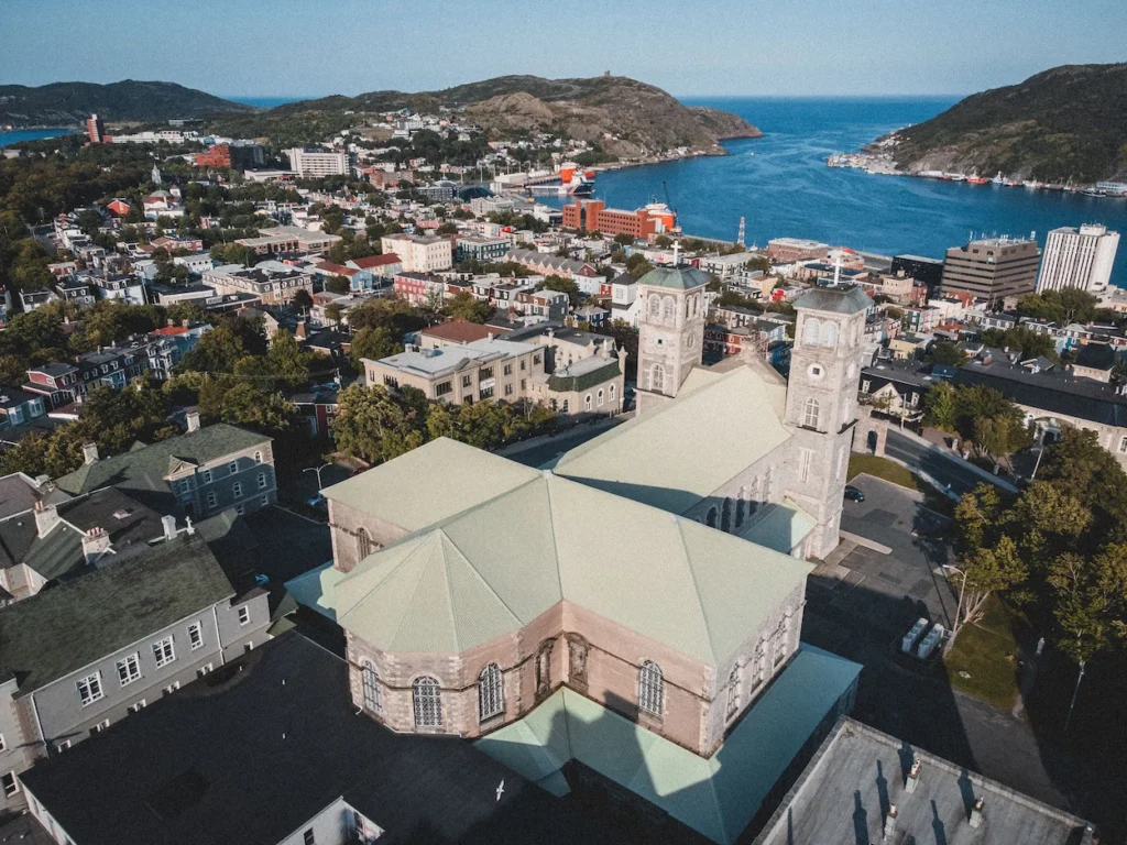 Aerial view of the green-roofed Basilica of St. John the Baptist facing the ocean harbor