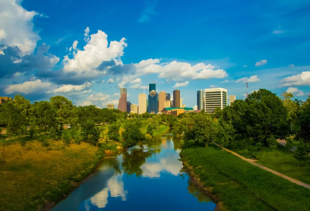 The downtown Houston skyline and fluffy white clouds reflecting on Buffalo Bayou