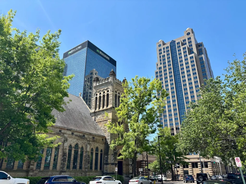 Cathedral Church of the Advent stone building in front of modern Birmingham Alabama skyscrapers