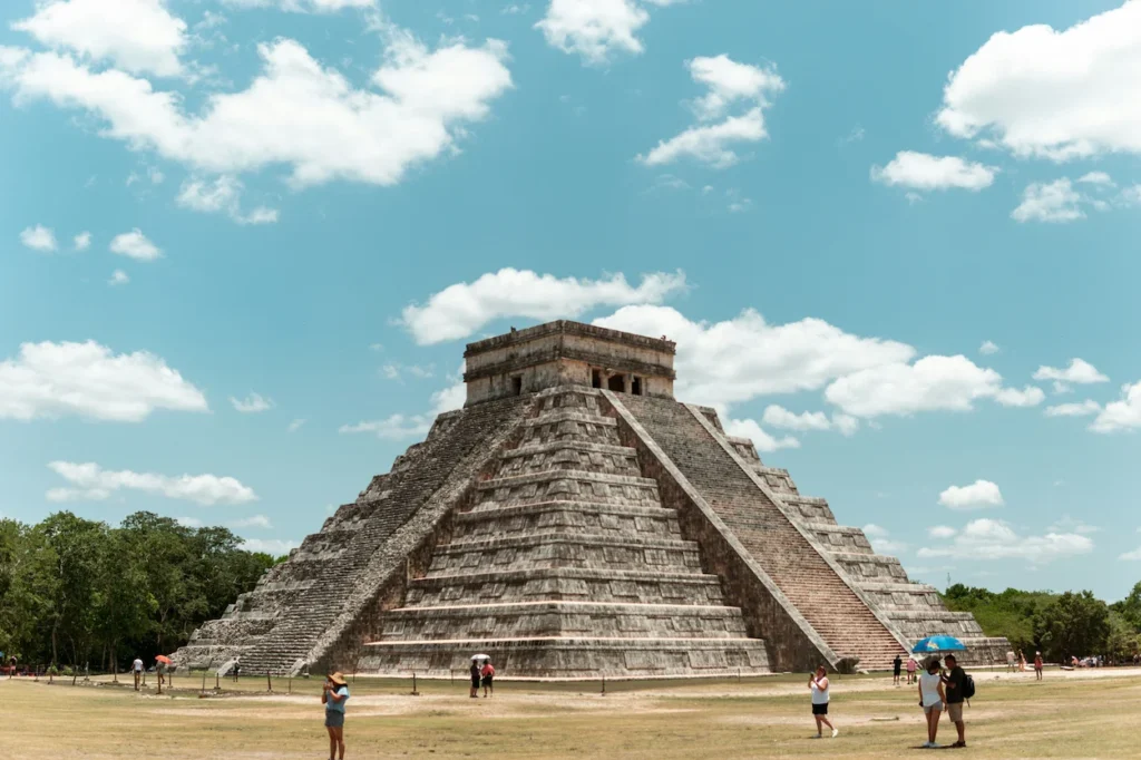 Ancient stone El Castillo pyramid at Chichen Itza under a blue sky with scattered clouds