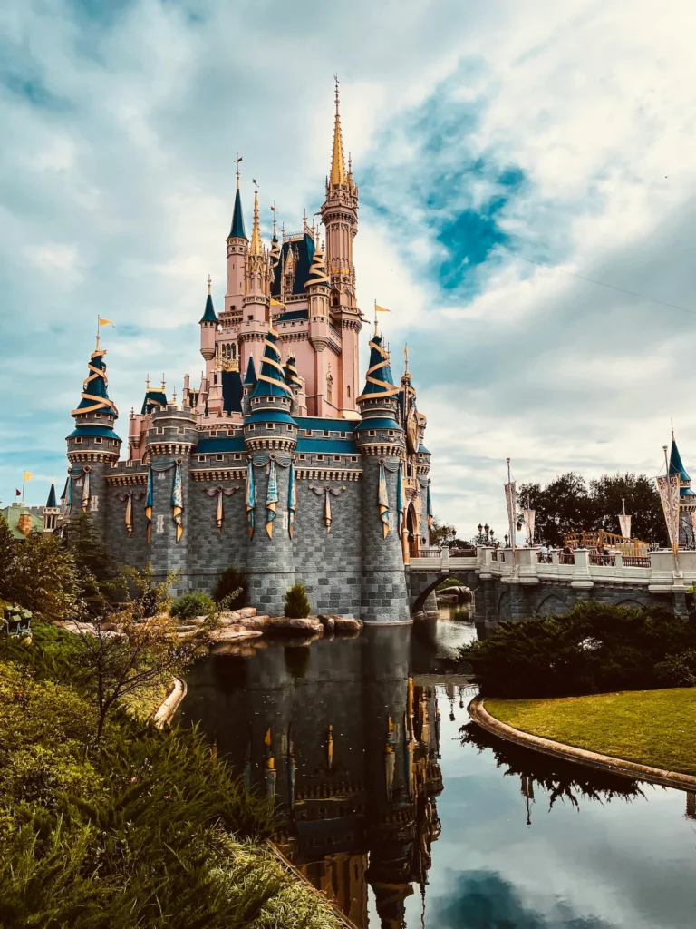 Cinderella Castle in Magic Kingdom reflecting in the water moat under a cloudy sky