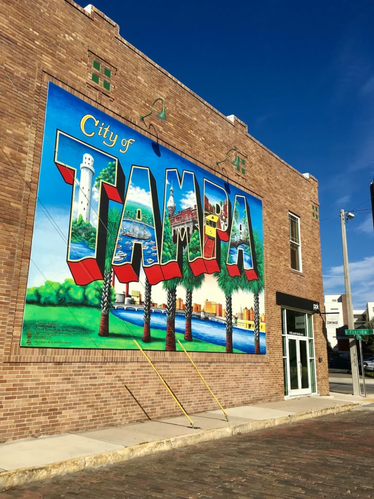 Colorful "City of Tampa" postcard mural painted on a brick building street corner