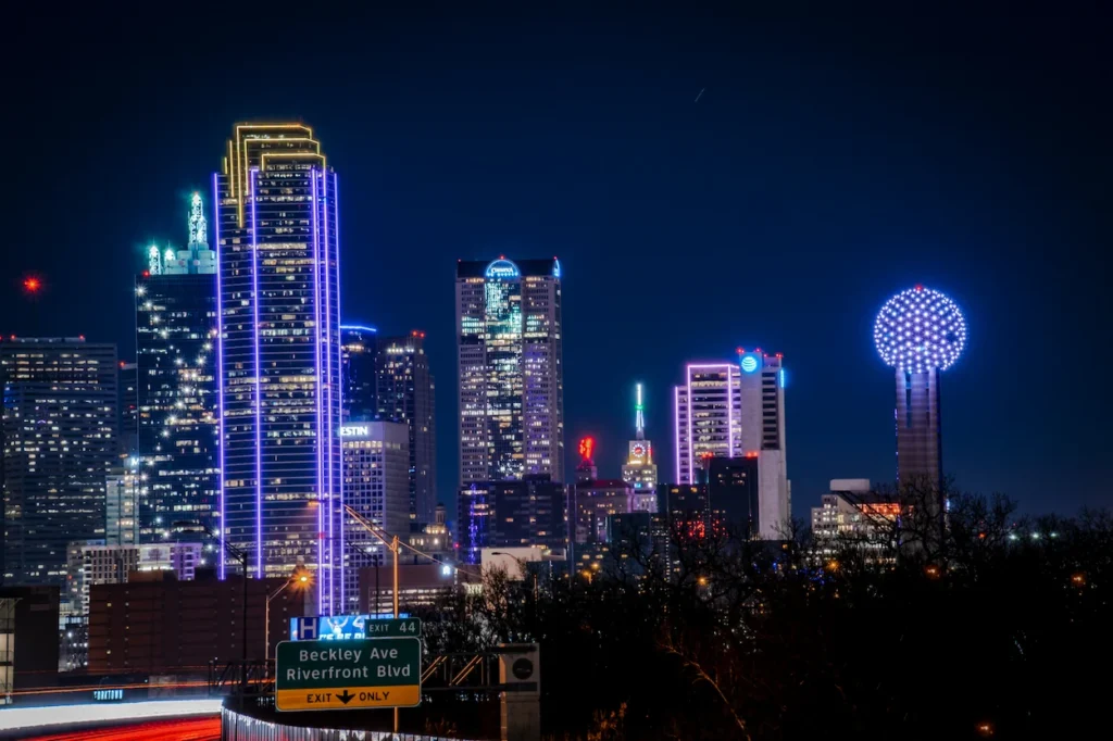 Brightly lit downtown Dallas skyline at night highlighting the illuminated Reunion Tower ball