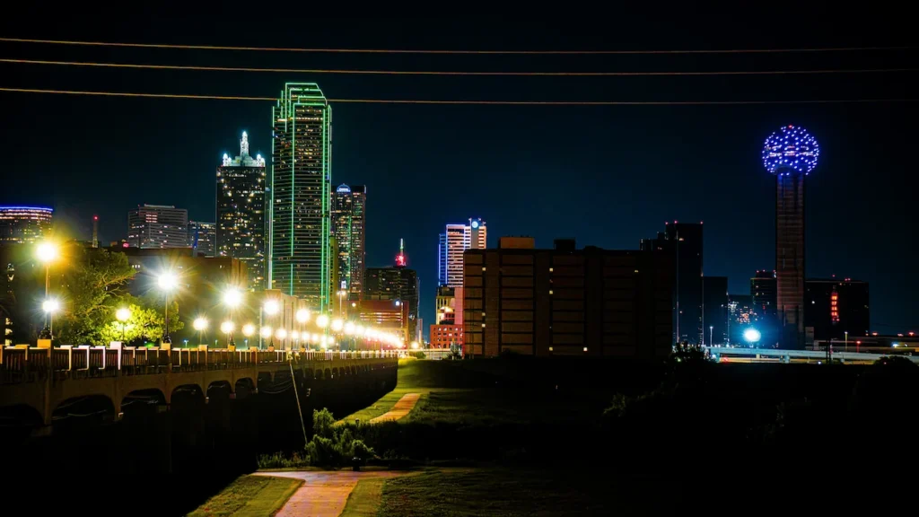 Downtown Dallas skyline illuminated at night featuring Reunion Tower and the green neon lights of the Bank of America Plaza