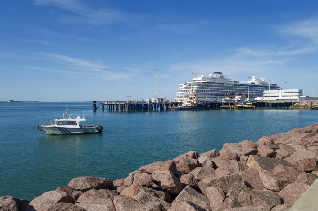 A large white cruise ship docked at Fort Hill Wharf in Darwin with a patrol boat nearby