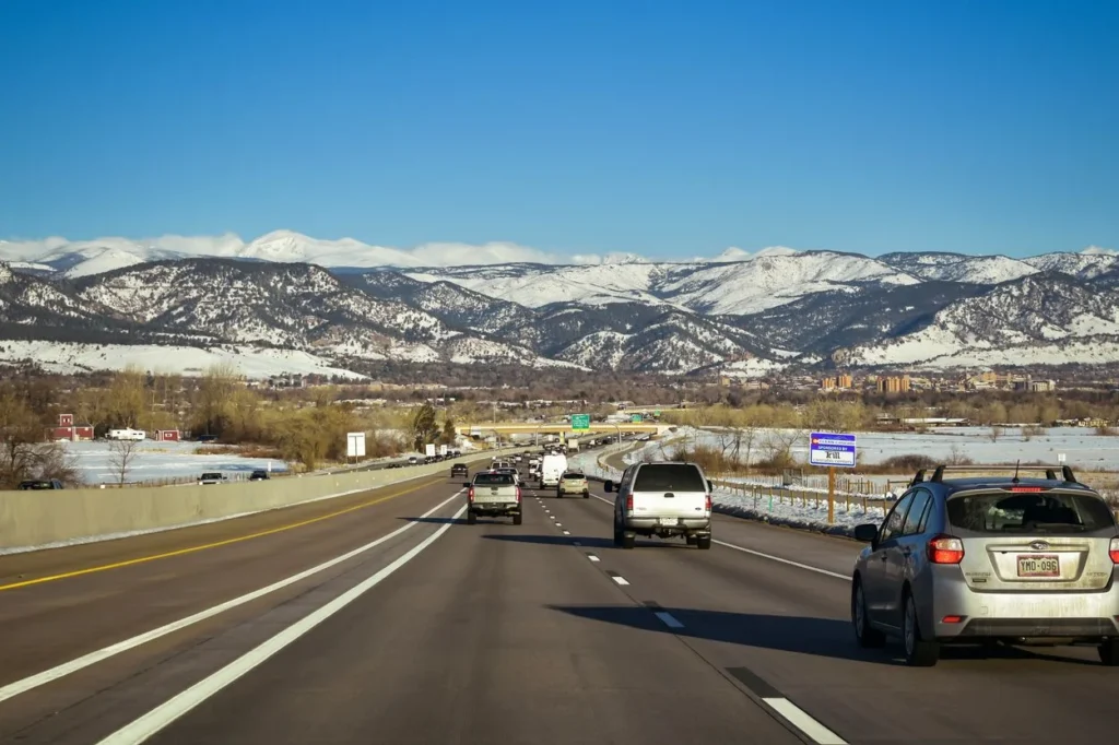 Highway road leading toward the snow-capped Rocky Mountains near Denver