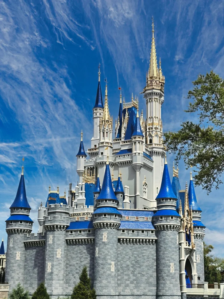 Cinderella Castle with grey stone walls and bright blue spires under a wispy blue sky