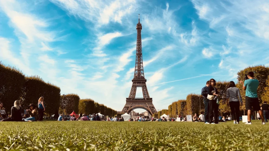 Eiffel Tower soaring above the open green lawns of Champ de Mars park under a clear sky