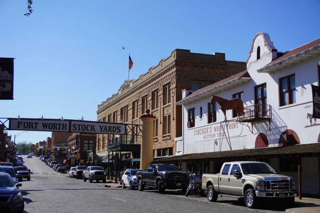 Fort Worth Stockyards entry sign over a cobblestone street lined with historic western buildings in Texas