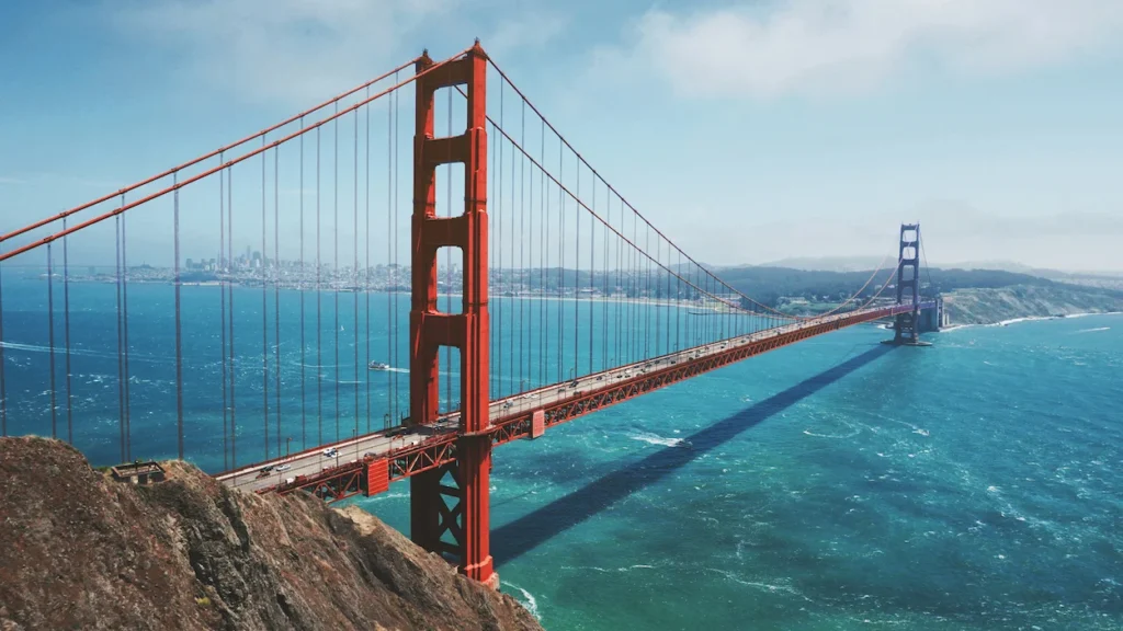 Golden Gate Bridge spanning across the blue San Francisco Bay water under a clear blue sky