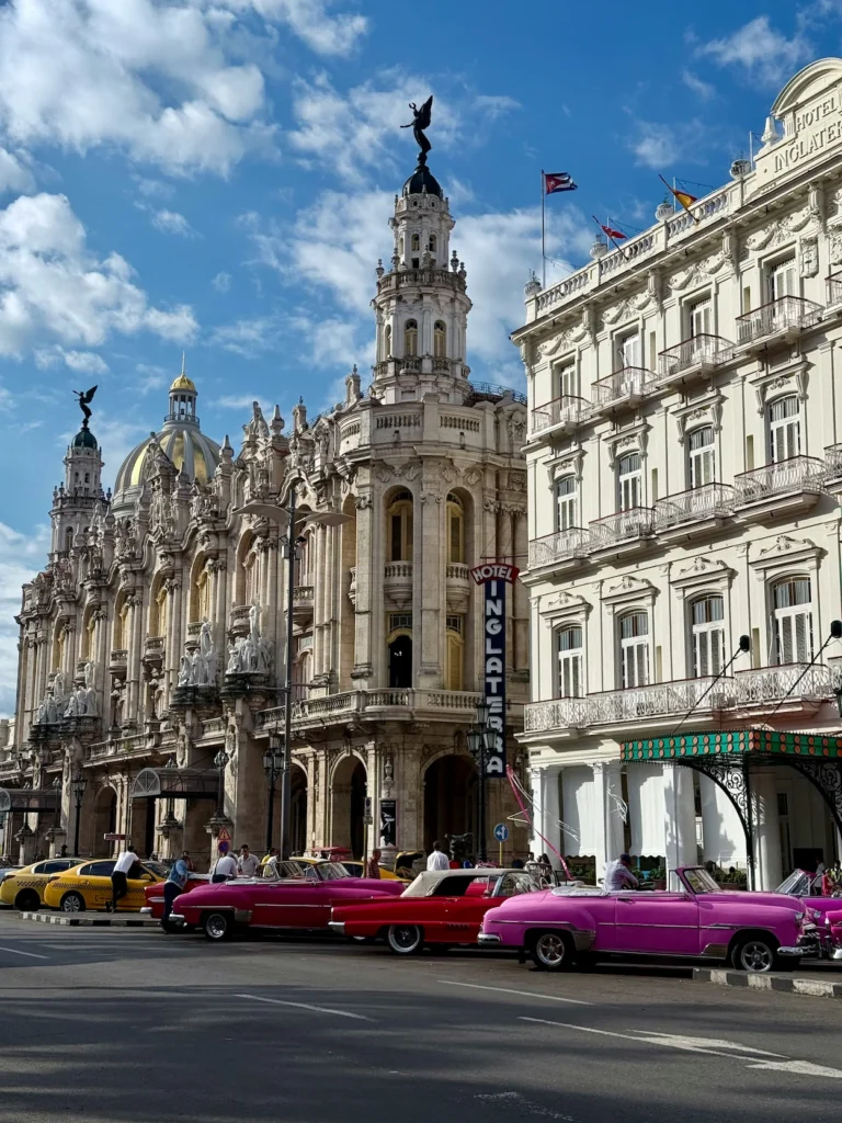 Classic pink convertibles parked on the street outside the ornate Gran Teatro and Hotel Inglaterra buildings in Havana