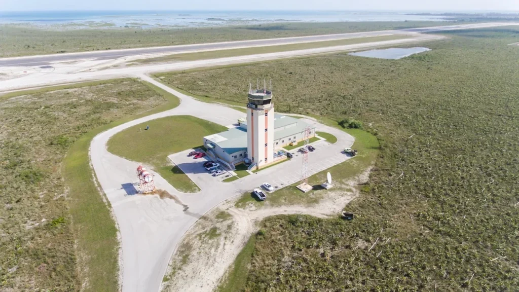 Aerial view of an airport control tower and runway surrounded by green shrubland
