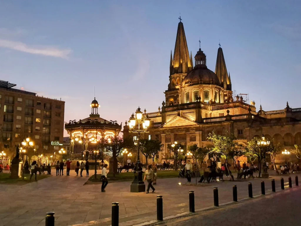 The illuminated Guadalajara Cathedral and its central kiosk at dusk